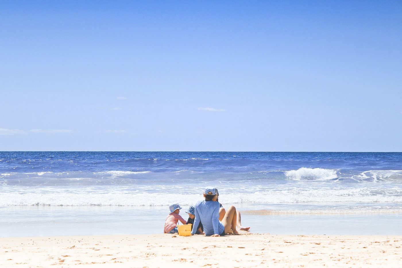 A family sitting on a wide sandy beach